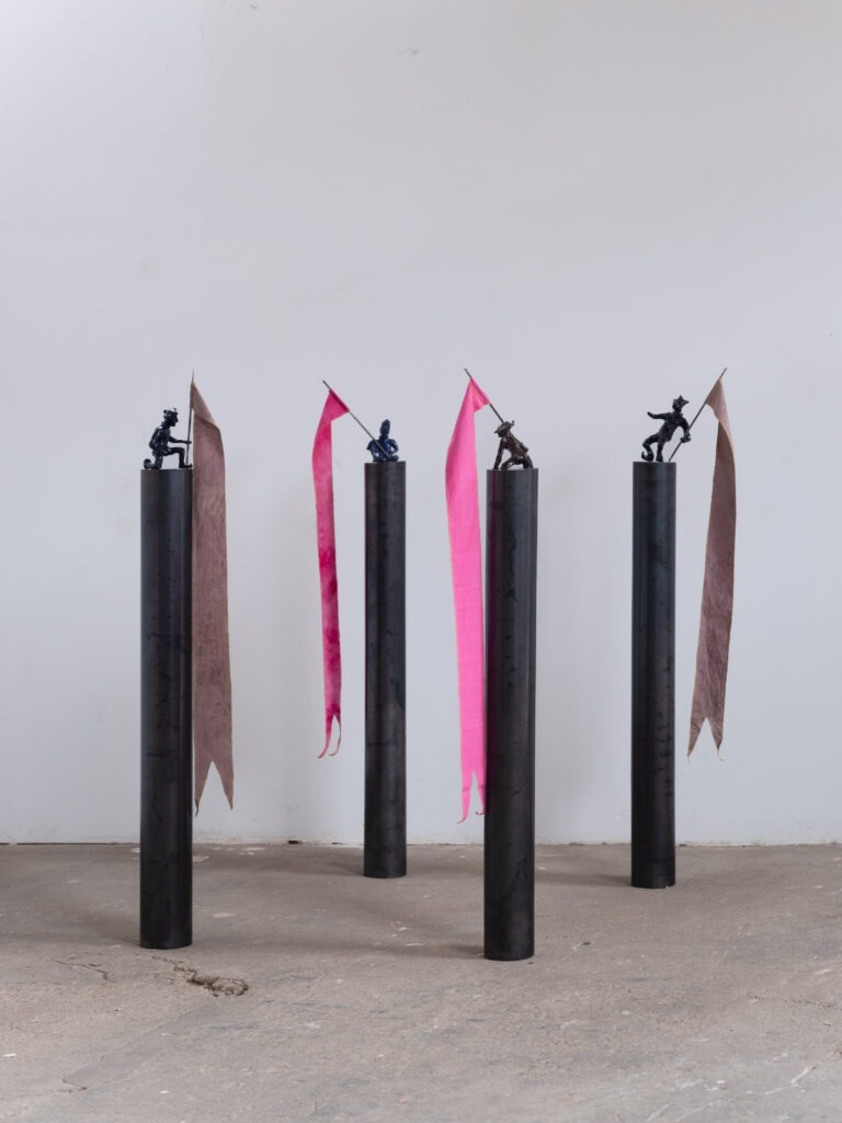 Creuze Joris-LE BAL DES ARDENTS, deuxième séquence, 2025-Personnages céramique,drapeau aux teintes identiques des drapeaux de 7 mètres, socle en acier, hauteur 120cm, Installation aux dimensions variables-@Anne Eppler